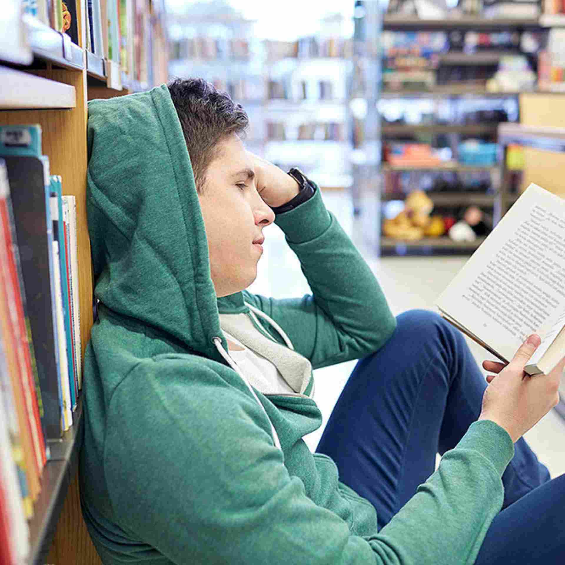 Она сидит в библиотеке. Люди в библиотеке. Сидит в библиотеке. Чтение в библиотеке. Молодой человек в библиотеке.